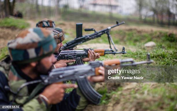 Indian army troopers aim their rifles towards a residential house where suspected rebels are trapped during a gun battle between Indian government...