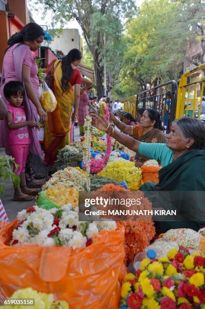 Indian vendors sell flower garlands to customers at a market in Bangalore on March 28 on the eve of Ugadi festival. The Hindu New Year is celebrated...