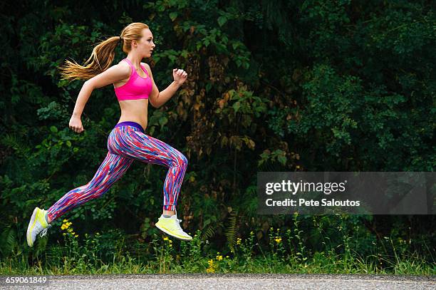 teenage female runner running on rural road - girls in leggings stock-fotos und bilder