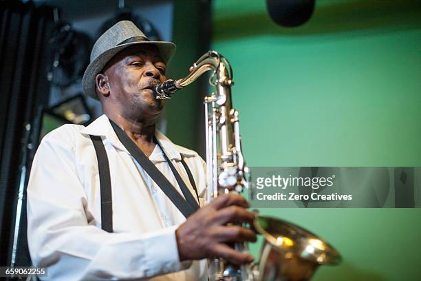 male musician in recording studio, playing saxophone - saxophone stock-fotos und bilder