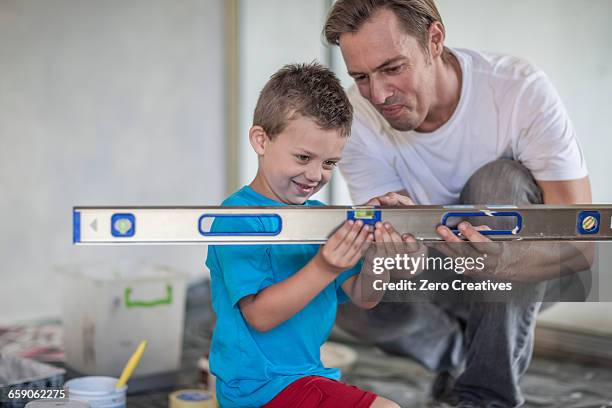 builder teaching son to use spirit level - waterpas stockfoto's en -beelden