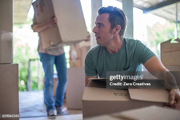 moving house: couple lifting cardboard boxes - box lifting technique stock-fotos und bilder