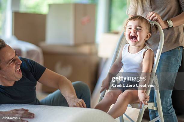 moving house: father and daughter laughing, daughter sitting on step stool - step stool imagens e fotografias de stock