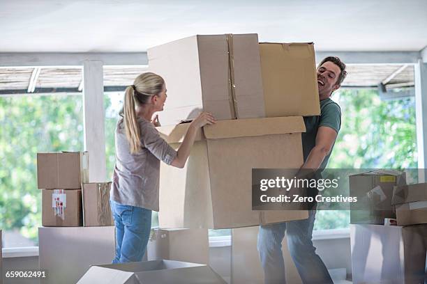 moving house: couple lifting cardboard boxes - box lifting technique stock-fotos und bilder