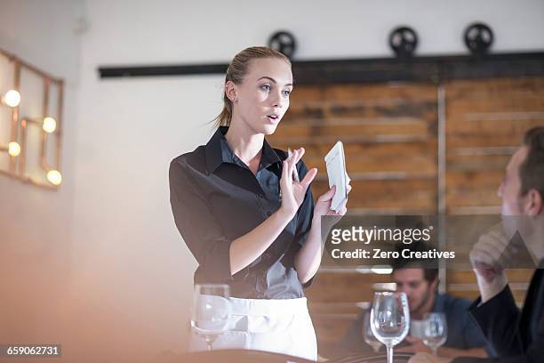 waitress explaining to customer in restaurant - waitress fotografías e imágenes de stock