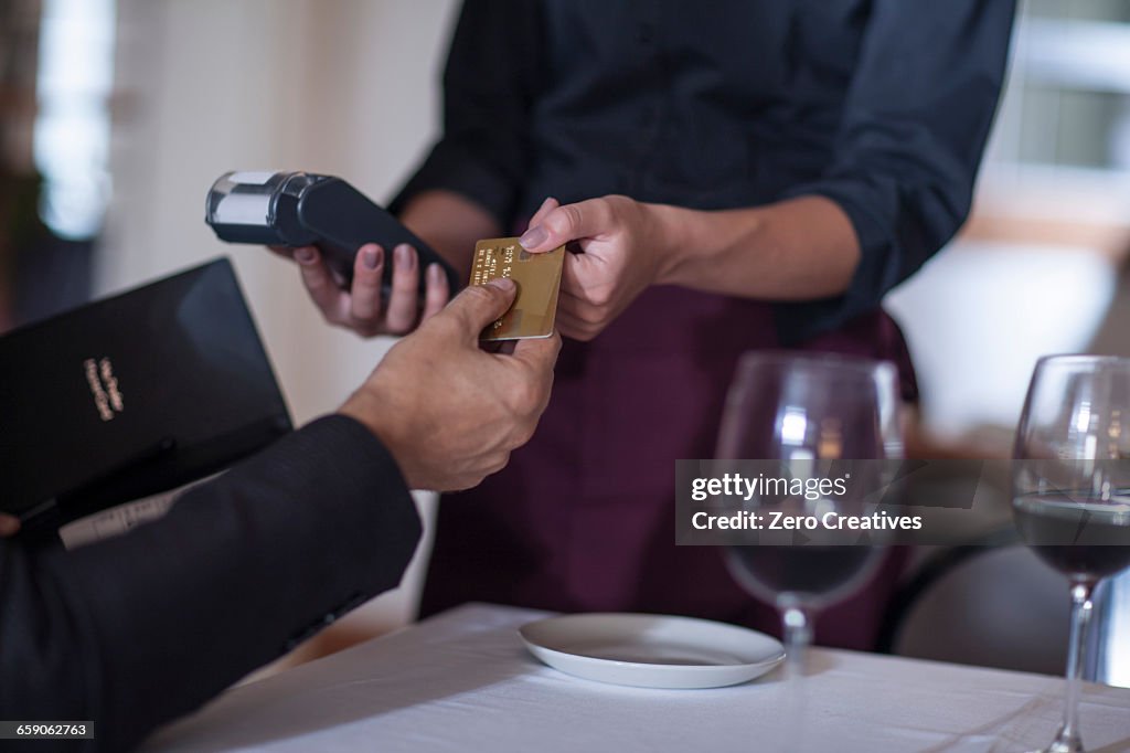 Customer paying with credit card to waitress in restaurant