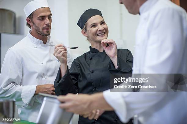 chefs chatting and tasting food in kitchen - chef tasting stock pictures, royalty-free photos & images