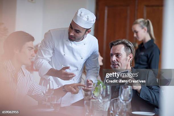 chef chatting with customers in restaurant - chef coat stock pictures, royalty-free photos & images