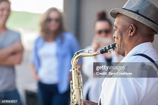 street musician, playing saxophone, entertaining pedestrians - busker stock pictures, royalty-free photos & images