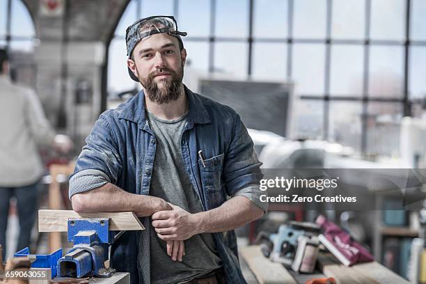 portrait of young male carpenter in antique restoration workshop - wood worker posing stock-fotos und bilder