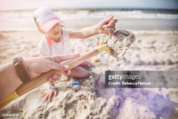 personal perspective of mother on beach holding shovel of sand for daughter - mobile alabama stock pictures, royalty-free photos & images