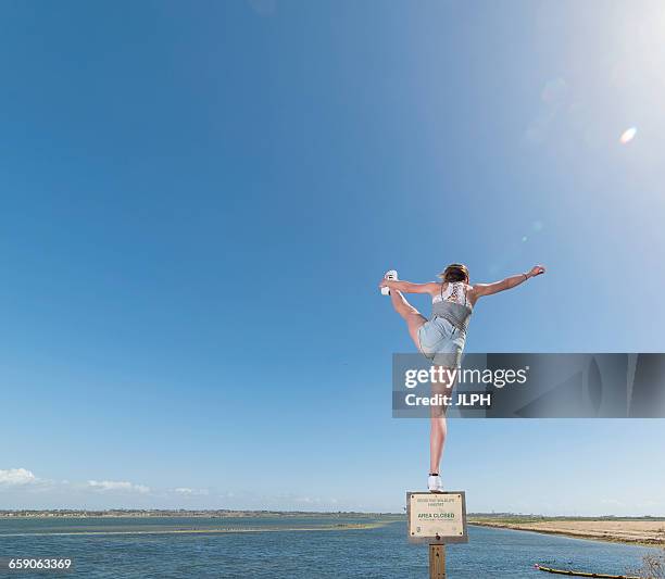 girl balancing on beach signage - huntington beach sign stock pictures, royalty-free photos & images