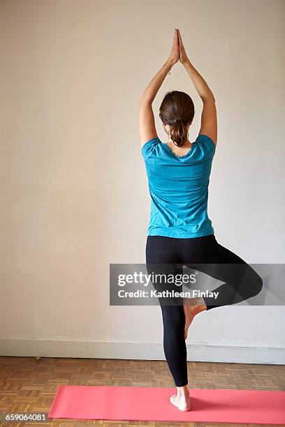 rear view of woman on one leg, arms raised in yoga position - spandex stock pictures, royalty-free photos & images