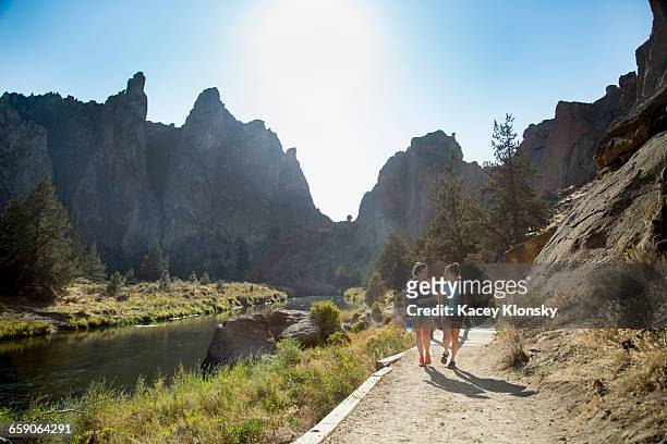 hikers hiking along path by river - smith rock state park stockfoto's en -beelden