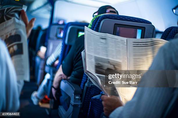 passengers reading newspapers on board flight - bulletin board stockfoto's en -beelden
