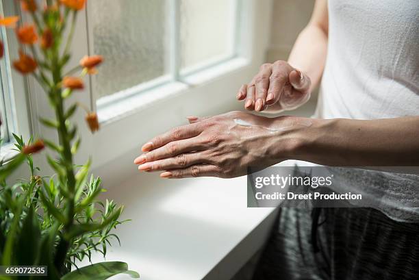 midsection of a young woman applying cream on her hand, munich, bavaria, germany - applying sunscreen stock pictures, royalty-free photos & images