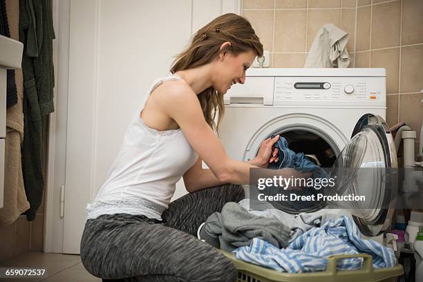 young woman taking laundry out of washing machine, munich, bavaria, germany - washing basket stock-fotos und bilder