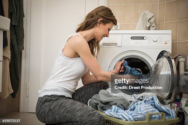 young woman taking laundry out of washing machine, munich, bavaria, germany - laundry basket imagens e fotografias de stock