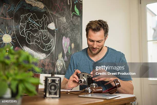 man repairing antique camera in dining room, munich, bavaria, germany - maquina fotografica antiga imagens e fotografias de stock