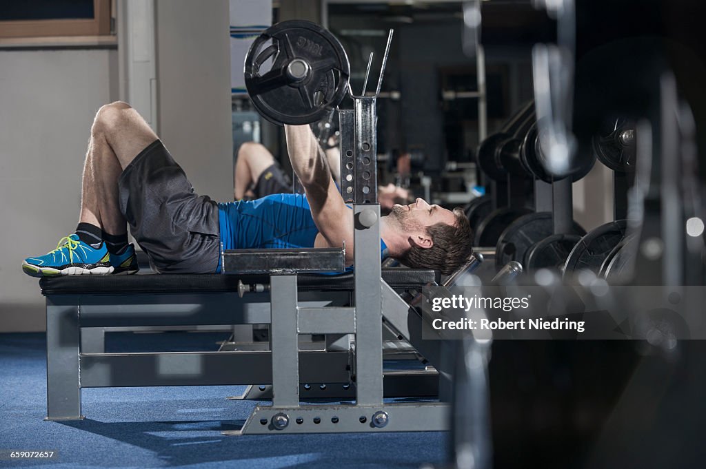 Mid adult man doing bench press in the gym, Bavaria, Germany