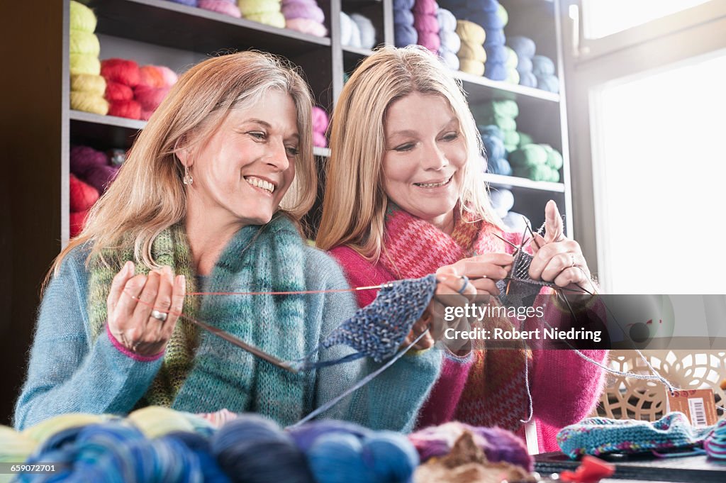 Two women knitting muffler in coffee shop and smiling, Bavaria, Germany