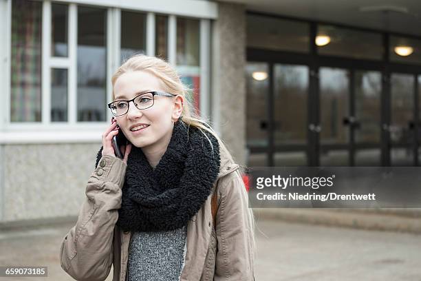 university student talking on mobile phone and leaving out of college school, bavaria, germany - bavaria girl stockfoto's en -beelden