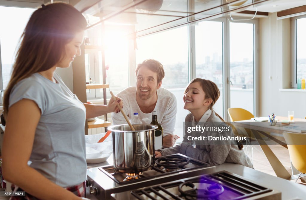Mother cooking in the company of her husband and daughter