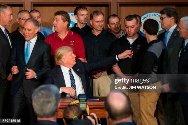 Surrounded by miners from Rosebud Mining, US President Donald Trump hands the pen with which he signed the Energy Independence Executive Order at the...