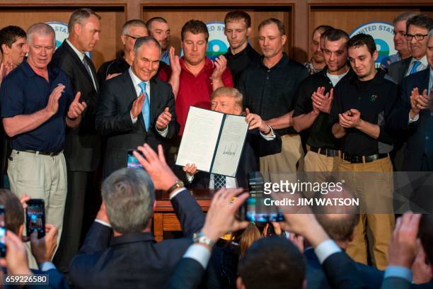 Surrounded by miners from Rosebud Mining, US President Donald Trump shows the signed Energy Independence Executive Order at the Environmental...