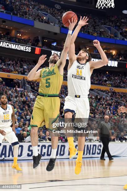 Matt Farrell of the Notre Dame Fighting Irish drives to the basket over Nathan Adrian of the West Virginia Mountaineers during the Second Round of...