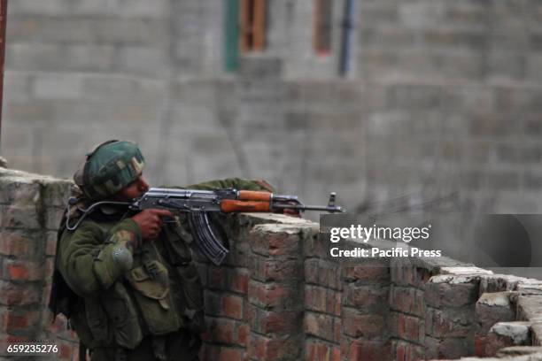 An Indian army soldier taking position to fire towards gun battle site in Chadoora area of Central Kashmirs Budgam district. One militant and three...