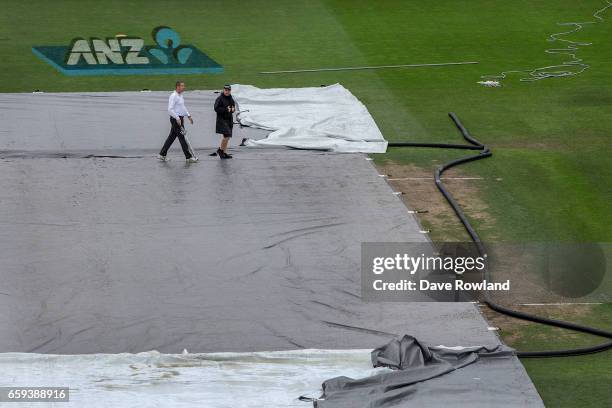 Reserve Umpire Chris Brown and Head Groundsman Karl Johnson inspect the pitch after rain is delaying the start of day five of the Test match between...