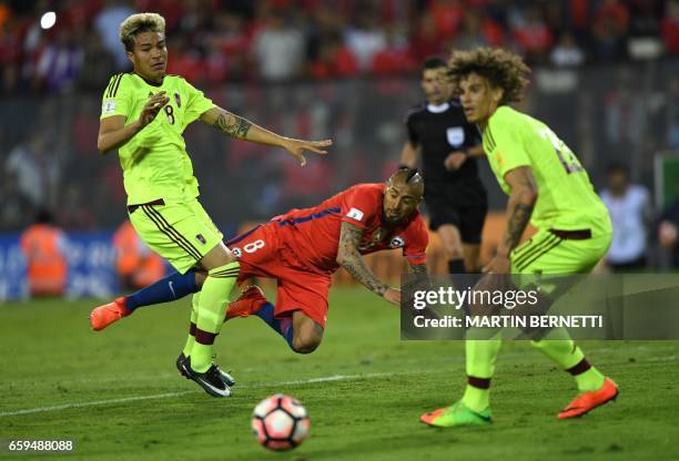 Chile's midfielder Arturo Vidal falls and loses the ball between Venezuela's midfielder Adalberto Penaranda and defender Rolf Feltscher during their...