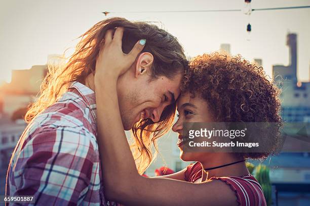 couple embracing on urban rooftop - face to face fotografías e imágenes de stock
