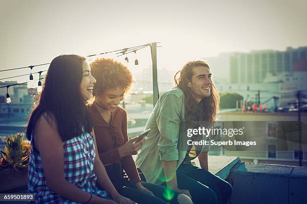 friends sharing a laugh on urban rooftop - los angeles events stockfoto's en -beelden