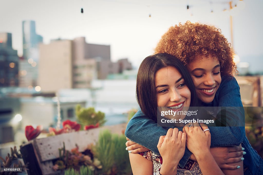 Friends hugging on urban rooftop