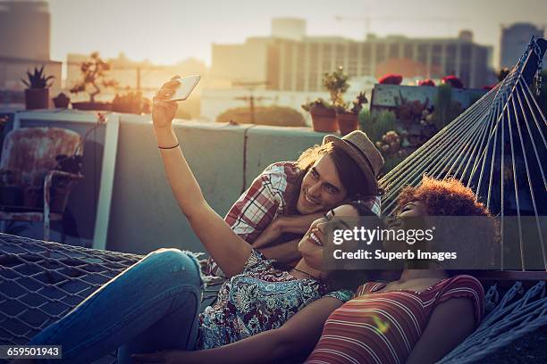 friends taking a selfie on urban rooftop - sunset freinds city stock-fotos und bilder