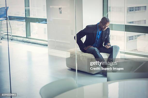 businessman checks smartphone in office - black blazer photos et images de collection