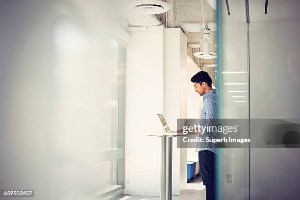 man working on laptop computer in business office - gray shirt stock pictures, royalty-free photos & images