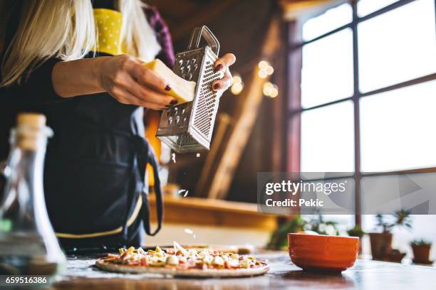 frauen hand reiben den käse auf der pizza - reiben stock-fotos und bilder