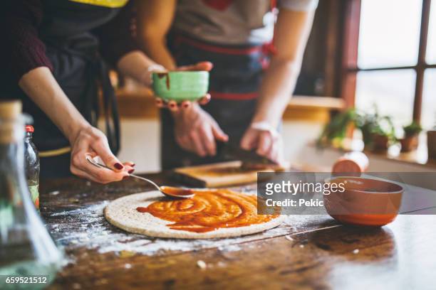 giovane coppia che fa pizza fresca in cucina - preparazione foto e immagini stock