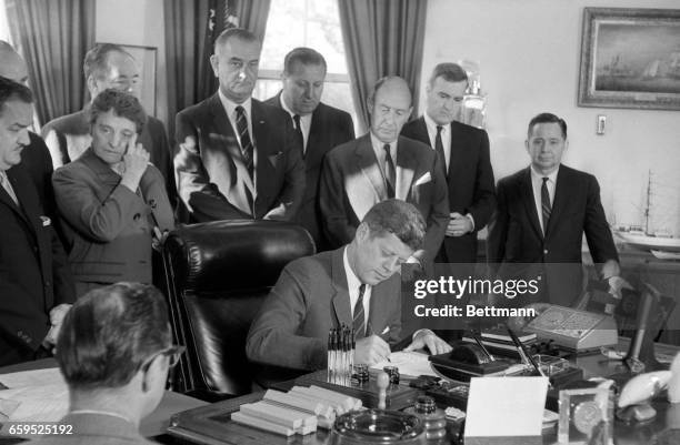 President Kennedy signs into law today a bill to allow the U.S. Purchase of up to $200 000 United Nations bond issue. Looking on during the White...