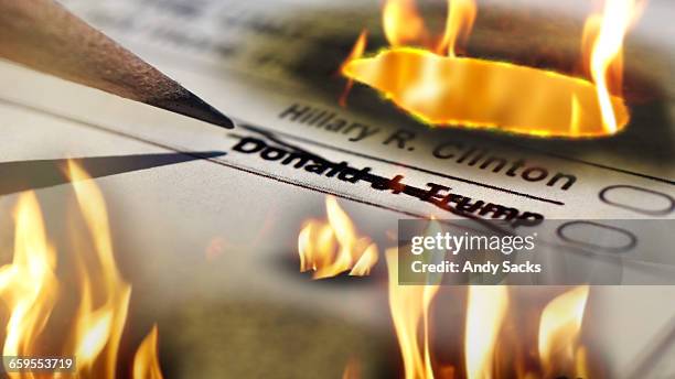 voter crosses out trump's name from a presidential ballot that is engulfed in flames. - chelsea michigan stock pictures, royalty-free photos & images