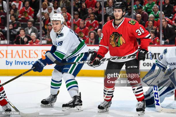 Nikita Tryamkin of the Vancouver Canucks and Ryan Hartman of the Chicago Blackhawks watch for the puck in the third period at the United Center on...