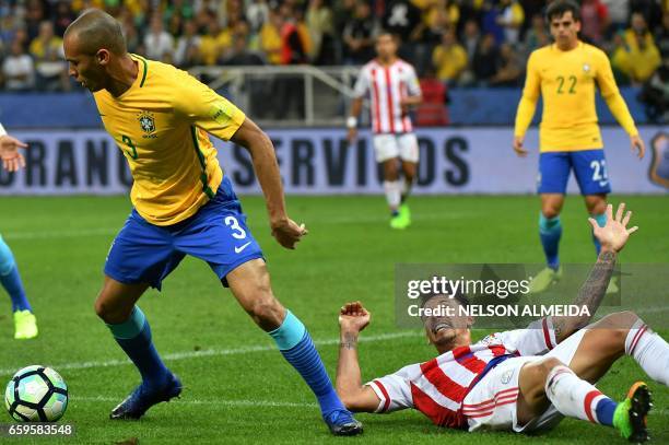 Paraguay's midfielder Hernan Perez falls behind Brazil's defender Miranda during their 2018 FIFA World Cup qualifier football match in Sao Paulo,...