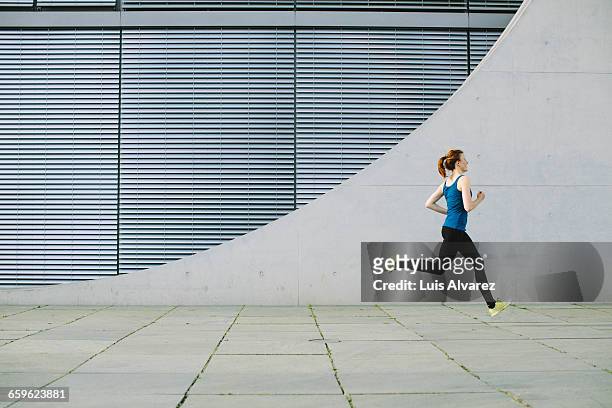 woman running in front of a building - jogging photos et images de collection