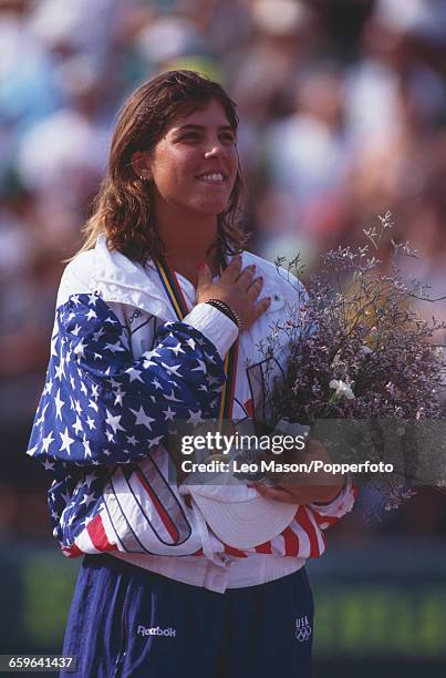 American tennis player Jennifer Capriati of the United States team celebrates on the medal podium after finishing in first place after beating Steffi...