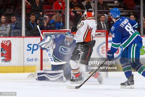 Nikita Tryamkin of the Vancouver Canucks and Antoine Vermette of the Anaheim Ducks look on as Vancouver goaltender Ryan Miller blocks a shot during...