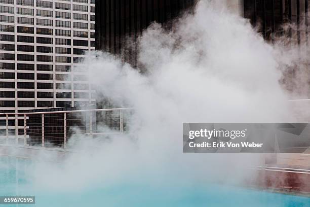 steam coming off rooftop pool in downtown area - rooftop pool stock-fotos und bilder