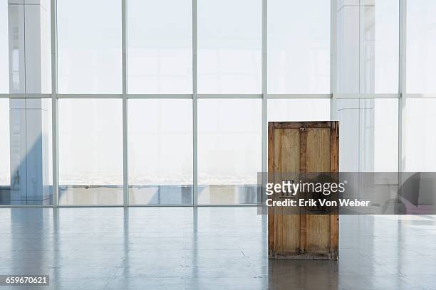 wooden shipping crate in large empty office space - crate stock pictures, royalty-free photos & images